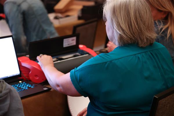 Deaf Blind Limitless conference attendee adjusting a page blaster before embossing